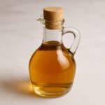 Cruet di vetro trasparente con aceto ambrato su fondo neutro