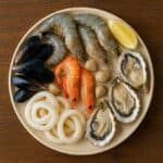 Piatto con frutti di mare tra cui: gamberi, cozze, vongole, ostriche, anelli di calamaro e limone