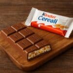 Barretta Kinder Cereali aperta con ripieno di cereali croccanti su tavolo in legno rustico