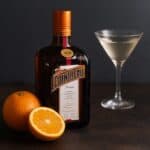 Cointreau con arance fresche e cocktail trasparente su fondo scuro