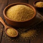 Bulgur non cotto in una ciotola rustica accanto a un cucchiaio e spezie assortite