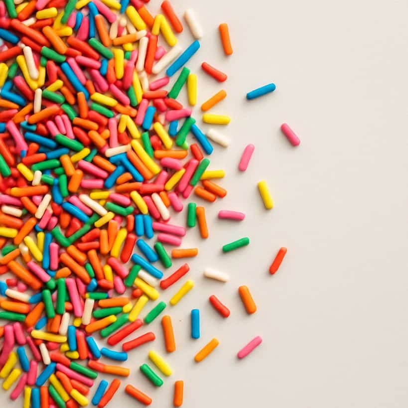 Codette zuccherate colorate sparse su superficie avorio