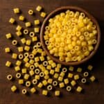 Ditalini di pasta crudi sparsi su tavolo in legno con ciotola in alto a destra