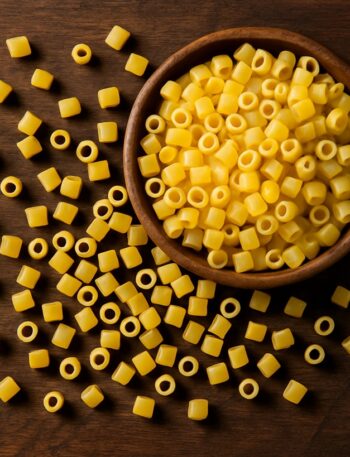 Ditalini di pasta crudi sparsi su tavolo in legno con ciotola in alto a destra