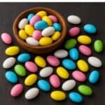 Dragees ovali dai colori pastello in ciotola di legno e sparsi sul tavolo
