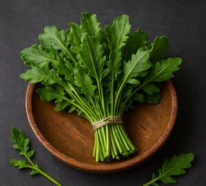 Mazzo di erbette di campo fresche con foglie verdi frastagliate in ciotola di legno su fondo scuro