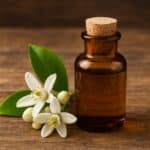 Piccola bottiglia di vetro ambrato con essenza di fiori d’arancio su fondo rustico