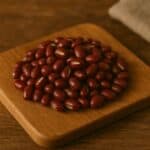 Mucchietto di fagioli azuki rossi con solco bianco su tagliere rustico