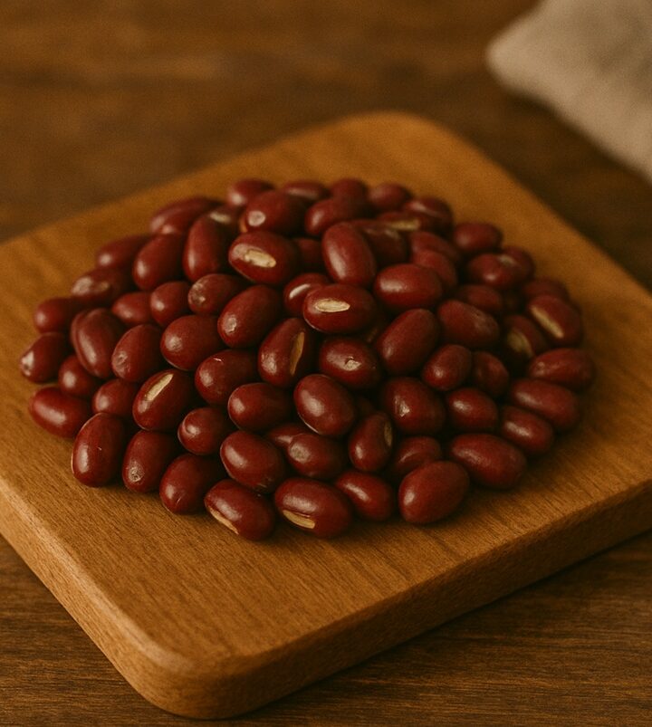 Mucchietto di fagioli azuki rossi con solco bianco su tagliere rustico