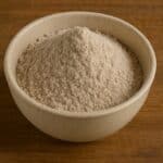 Ciotola in ceramica con farina di grano saraceno finemente macinata su sfondo in legno