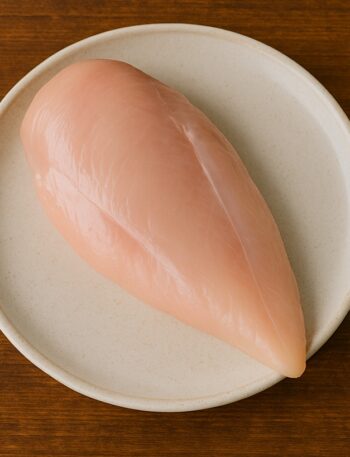 Petto di pollo crudo senza pelle né osso su piatto tondo chiaro