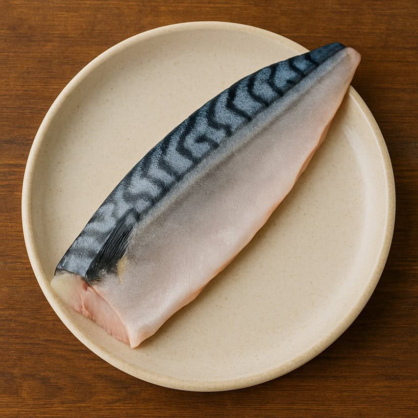 Trancio di sgombro con pelle argentata e striature nere su piatto in ceramica