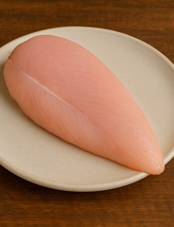 Petto di tacchino crudo con superficie liscia e rosa chiaro su piatto tondo