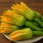 Mazzo di fiori di zucca gialli con gambo verde disposti su piatto chiaro