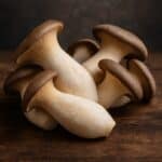 Gruppo di funghi cardoncelli con cappelli marroni e gambi chiari su tavolo in legno