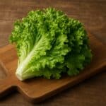 Cespo di lattuga verde fresca appoggiato su un tagliere di legno
