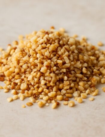 Granella di nocciole tostate su sfondo naturale chiaro