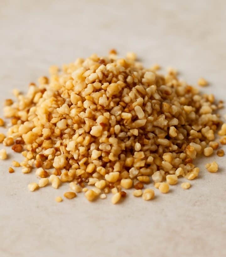 Granella di nocciole tostate su sfondo naturale chiaro