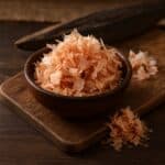 Katsuobushi in ciotola di legno su tagliere con blocco di tonnetto essiccato