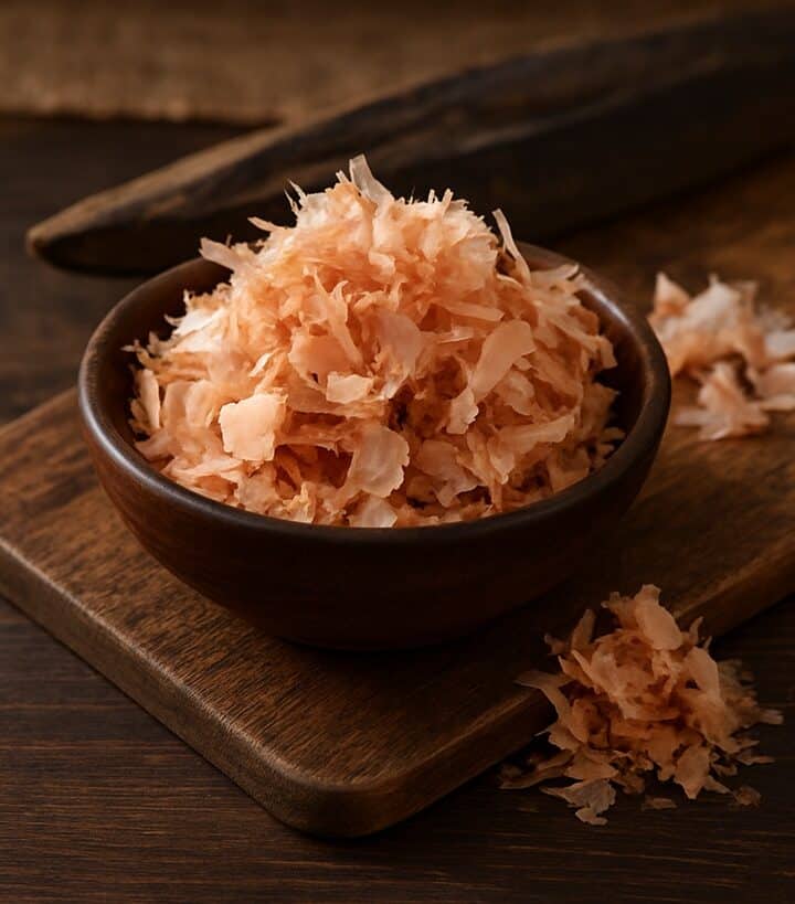 Katsuobushi in ciotola di legno su tagliere con blocco di tonnetto essiccato