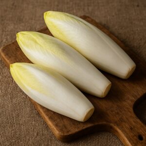 Indivia belga fresca disposta su tagliere in legno con sfondo in juta naturale