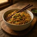 Noodles saltati in ciotola con cipollotto fresco e bacchette su tagliere rustico