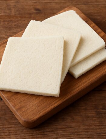 Pane per tramezzini quadrato e senza crosta su tagliere in legno