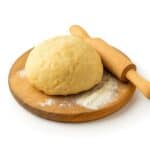 Immagine rappresentativa della categoria Impasti di Base: panetto di impasto su tagliere infarinato con mattarello