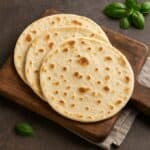 Piadina romagnola cotta e dorata su tagliere in legno con foglie di basilico