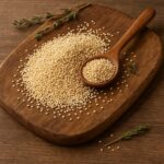 Semi di quinoa chiara con cucchiaio di legno su tagliere in legno