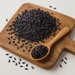 Riso Venere nero crudo su tagliere in legno con cucchiaio colmo