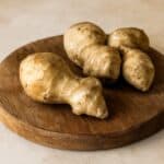 Gruppo di tuberi di topinambur su tagliere rotondo in legno