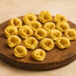 Tortellini fatti a mano disposti su tagliere in legno