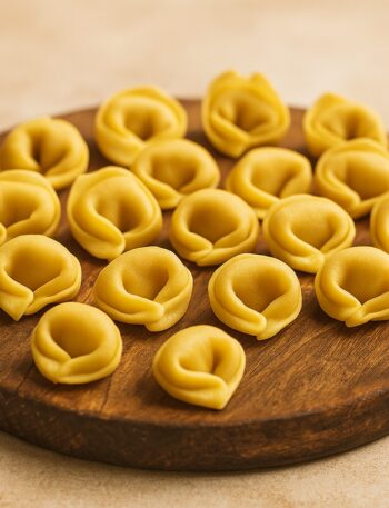 Tortellini fatti a mano disposti su tagliere in legno