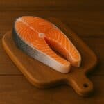 Trancio di salmone fresco con pelle su tagliere in legno naturale