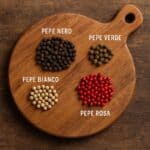 Pepe nero, bianco, verde e rosa su tagliere rustico in cucina