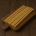 ziti crudi ordinatamente disposti su un tagliere in legno scuro