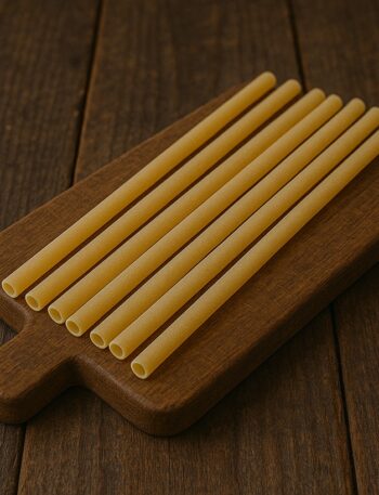ziti crudi ordinatamente disposti su un tagliere in legno scuro
