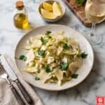 Piatto di insalata di carciofi crudi con scaglie di grana, prezzemolo fresco e olio extravergine su tavola in marmo