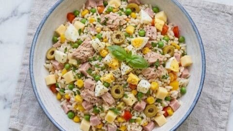 Insalata di riso classica servita in ciotola con tonno, uova, formaggio e verdure
