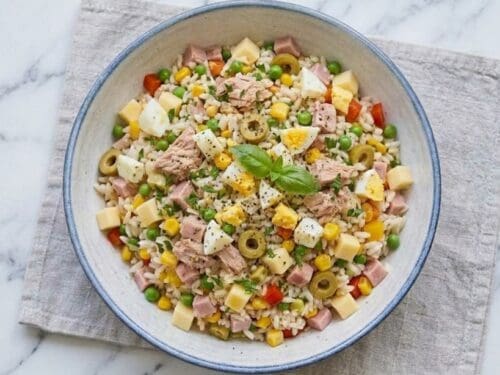 Insalata di riso classica servita in ciotola con tonno, uova, formaggio e verdure