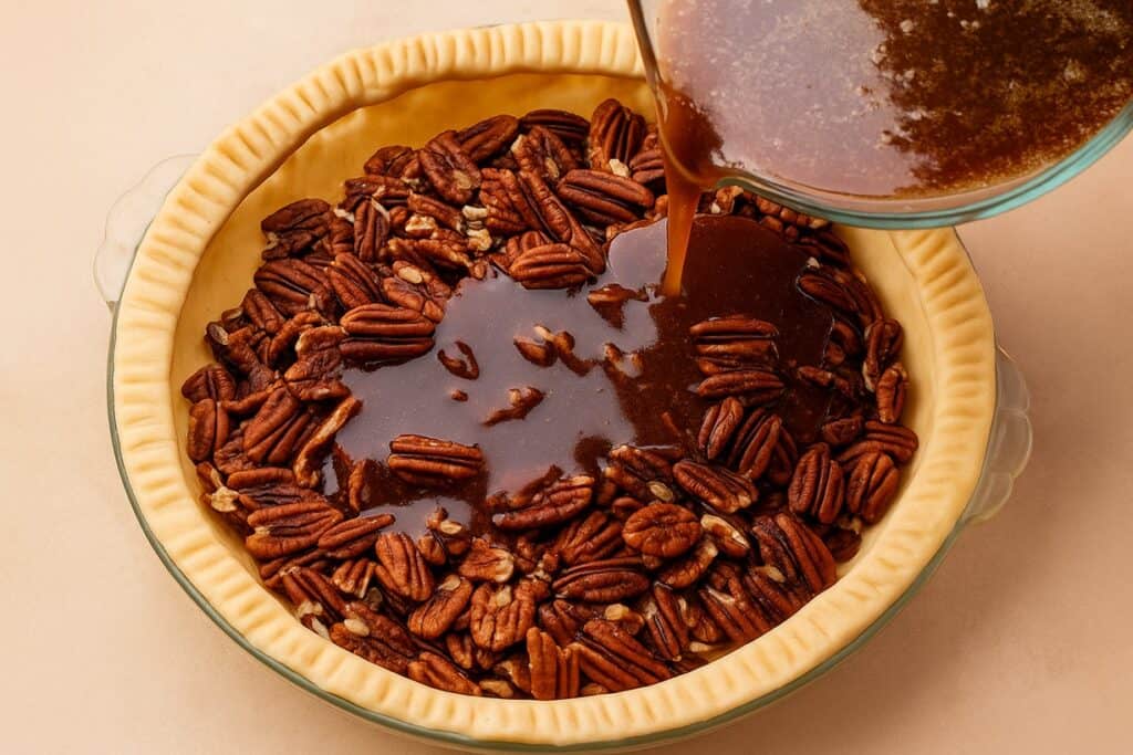 Ripieno caramellato versato sulle noci pecan nella base della torta