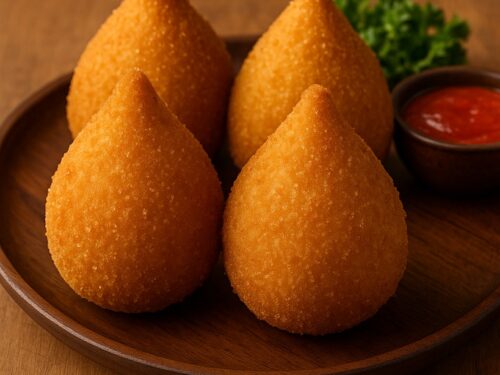Quattro coxinha brasiliane dorate servite con salsa rossa