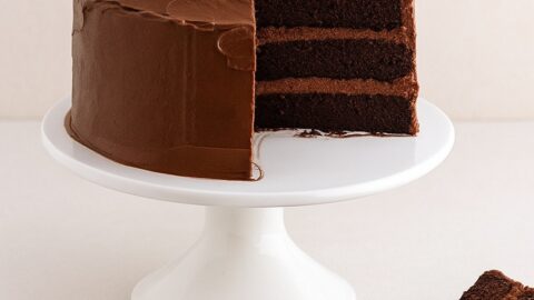 Devil’s Food Cake a tre strati con una fetta tagliata su alzata bianca