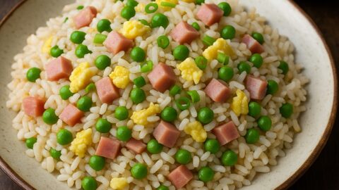 Riso cantonese con prosciutto, piselli e uova su piatto rustico