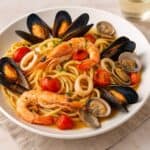 Piatto di spaghetti allo scoglio con gamberi, cozze, vongole, calamari e pomodorini