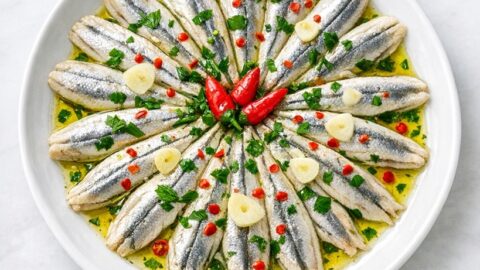 Alici marinate disposte a raggiera con olio, aglio, prezzemolo e peperoncino