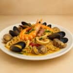Risotto alla pescatora cremoso con frutti di mare freschi servito in un piatto bianco