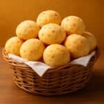 Pão de Queijo dorati in un cestino di vimini su sfondo caldo e luminoso