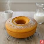 Ciambellone soffice dorato con zucchero a velo, intero su gratella da raffreddamento